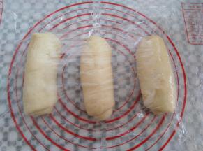 面团从下往上卷起来，收口处捏紧，盖上保鲜膜再次松弛10分钟