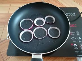 不粘锅里刷一点点油，放入洋葱圈小火加热