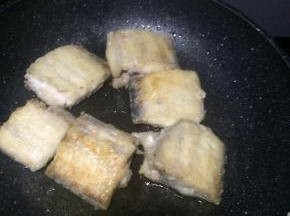 平底锅内倒入适量食用油，放入沾满干淀粉的带鱼段，小火煎制。