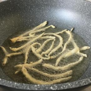 锅里放入油，油温七成热的时候，把菇一条条放入锅中