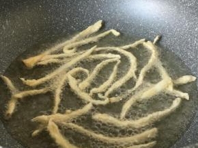 锅里放入油，油温七成热的时候，把菇一条条放入锅中