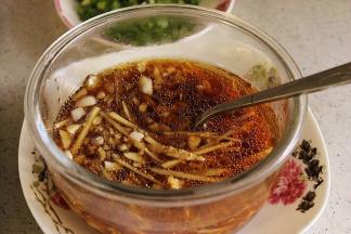 3、把蒜末、姜丝、生抽、盐、几滴香油放入碗里，倒少许凉开水化开