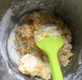 然后加鸡蛋，接着打发至顺滑，然后筛入面粉和奶粉，搅拌混合一下，然后放入切碎的芒果干，搅匀至没有干粉