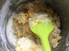 然后加鸡蛋，接着打发至顺滑，然后筛入面粉和奶粉，搅拌混合一下，然后放入切碎的芒果干，搅匀至没有干粉