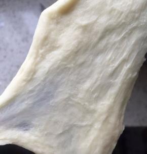 此时面团已经有一点延展性了，能拉出比较厚的膜，比较糙，容易断裂，此时把软化的黄油丢进去，继续4档揉，开始加黄油面团非常粗糙，时间久了，面团会非常光滑，加入黄油后，四档揉面12-15分钟左右