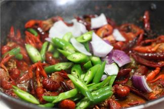 待虾肉焖至将要熟透,将炒勺移至旺火上收汁, 放入青蒜段, 青红椒，颠翻几下即可出勺装盘。