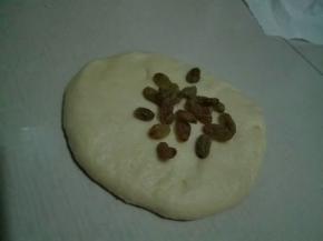 面团按扁，放入一半葡萄干