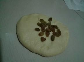 面团按扁，放入一半葡萄干