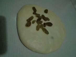 整形成圆形，再次按扁，放入剩余的葡萄干