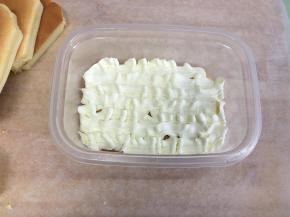 将一片蛋糕放入盒子里，表面挤上一层奶油。