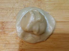 取一个事先炒好的绿豆馅放在擀开的面皮上，用虎品包紧