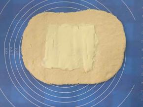 面团擀开成0.5cm左右，约3倍黄油片大的长方形，把黄油片放中间位置