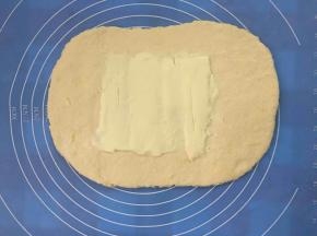 面团擀开成0.5cm左右，约3倍黄油片大的长方形，把黄油片放中间位置