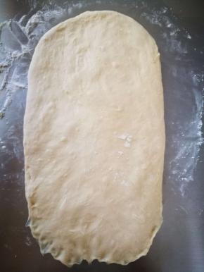 这里，我没有进行第一次醒发，直接整形后发酵，为什么呢？赶时间呀，傍晚做的，嘿嘿！成品口感影响不大，一样的柔软，加热后一样好吃，我吃面包都会加热后再吃！直接开始整形，将面团整成长椭圆形，光面向下！擀长一些，大概40厘米多