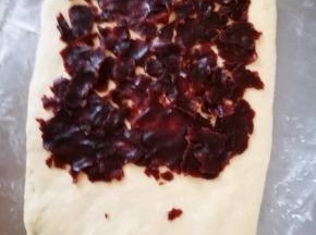 将豆沙压成薄片，薄薄的，均匀的铺在面团上