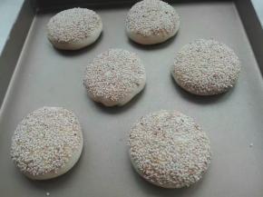 收口朝下，稍微按压成圆饼，表面刷蛋液或者水，表面沾上芝麻，再次轻轻按压，防止芝麻散落