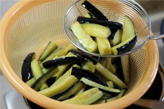 放入茄子炸至变色，捞出沥干。炸约不到一分钟，自己观察，稍稍变软即可捞出沥干，不然太软了不好吃。