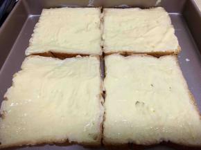 把吐司片放在烤盘上，将加热好的芝士酱浇在吐司片上，用刷子涂抹均匀