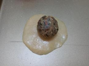 取一个饼皮，按压成圆饼，将五仁馅放在上面