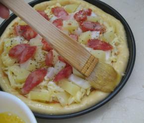 饼边缘刷上全蛋液，撒上披萨草和罗勒叶