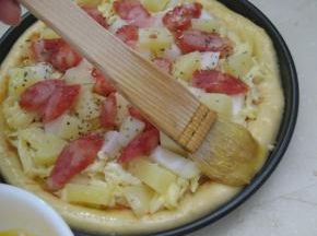 饼边缘刷上全蛋液，撒上披萨草和罗勒叶