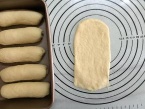 取一面团，用手稍加压扁后翻面，拿擀面杖擀成长舌形，底部压薄。