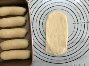 取一面团，用手稍加压扁后翻面，拿擀面杖擀成长舌形，底部压薄。
