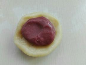 取一个水油皮剂子擀圆，包入一个油酥剂子