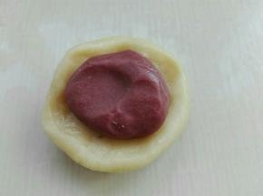 取一个水油皮剂子擀圆，包入一个油酥剂子