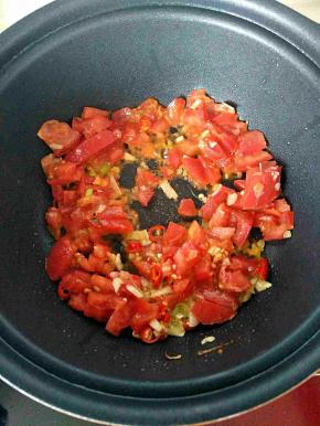 锅内放少许油倒入切碎的西红柿和葱蒜小米辣
