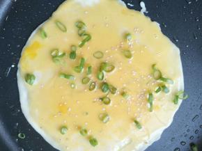 舀一小勺鸡蛋糊在面糊上，继续用工具快速刮开，撒少许小葱