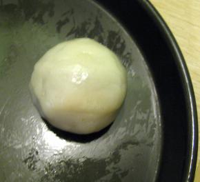 取一个冰皮压扁放上一个豆沙馅，然后将内馅全包住，收口向下滚圆