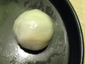 取一个冰皮压扁放上一个豆沙馅，然后将内馅全包住，收口向下滚圆