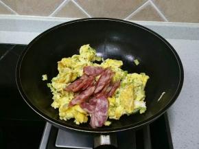 鸡蛋饼用铲子切成几块放入腊肠，翻炒均匀