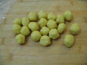 将面团放至案板上，揉搁在 成条开长形，用橡皮刮板分割成18等份。用双手揉成团球