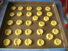 将圆球放 烤盘上，用大拇指在中间按扁，边缘裂开，