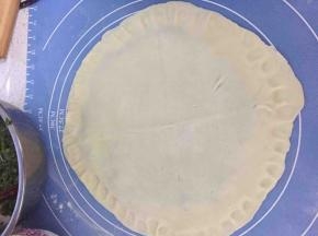 然后盖上一张饼皮，然后用手指均匀按压饼的边缘，全部按好