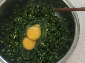 然后加入两颗鸡蛋，根据韭菜的多少来加鸡蛋，我这里就用了一小把韭菜，直接加鸡蛋饼烙出来更柔软，这里你也可以先把鸡蛋炒熟了