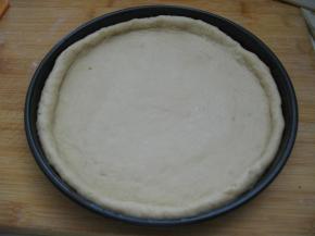 披萨盘提前抹油，将擀好的面皮放入批萨盘内，用手按压面皮，把面皮撑至与盘子同样大，边缘挤出一圈圆边