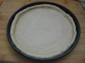 披萨盘提前抹油，将擀好的面皮放入批萨盘内，用手按压面皮，把面皮撑至与盘子同样大，边缘挤出一圈圆边