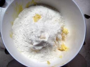 8. 低粉和奶粉混合均匀，过筛到黄油中。用橡皮刮刀把面粉与黄油拌匀，没有干粉的状态即可（由于酥皮较软易裂，可用保鲜膜包住面团，放冰箱冷藏20分钟后再取出）；
