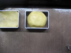 13. 把凤梨酥模具摆在烤盘上，取包好的凤梨酥生胚稍微搓长，放入模具中，轻轻把面团压平；