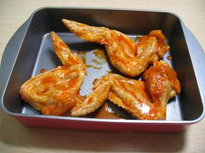 把腌好的鸡翅放入烤盘中，浇上一些调料汁