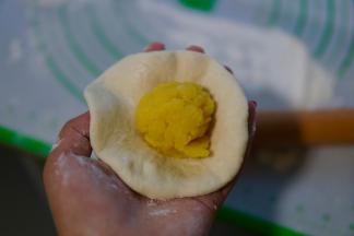 取一个面团包好奶黄馅，捏紧收口朝下。