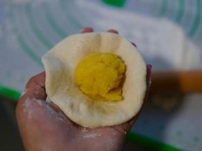取一个面团包好奶黄馅，捏紧收口朝下。