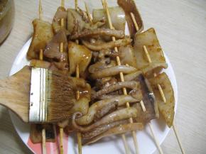 串好后，用毛刷把盘子里的酱汁刷到鱿鱼串上