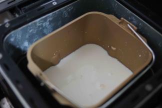 开水烫一下面包机桶，以后放入一部分牛奶，再放入菌粉，融化均匀后放入所有材料