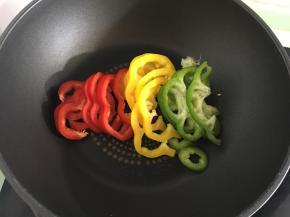 将青椒，红椒，黄椒放入加热的锅中。