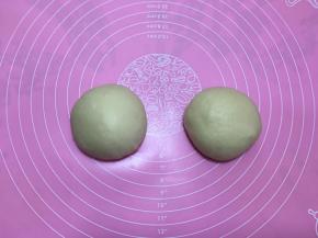 取出披萨面团，排气后平均分割成两份并揉圆。