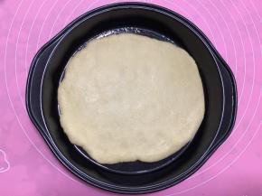 将擀好的饼皮放入披萨盘中。